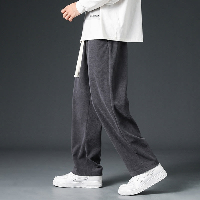 Pantaloni grigi in velluto a coste, indossati con maglia bianca e sneakers bianche, moda casual uomo, stile autunnale, abbigliamento confortevole.