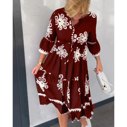 Abito rosso a fiori bianchi, maniche a tre quarti, indossato da donna bionda. Moda elegante, stile casual, accessori borsa bianca e scarpe sportive.