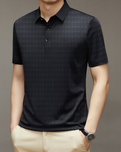 Uomo con polo nera a motivi geometrici, maniche corte, colletto classico, abbinata a pantaloni beige. Stile casual elegante.