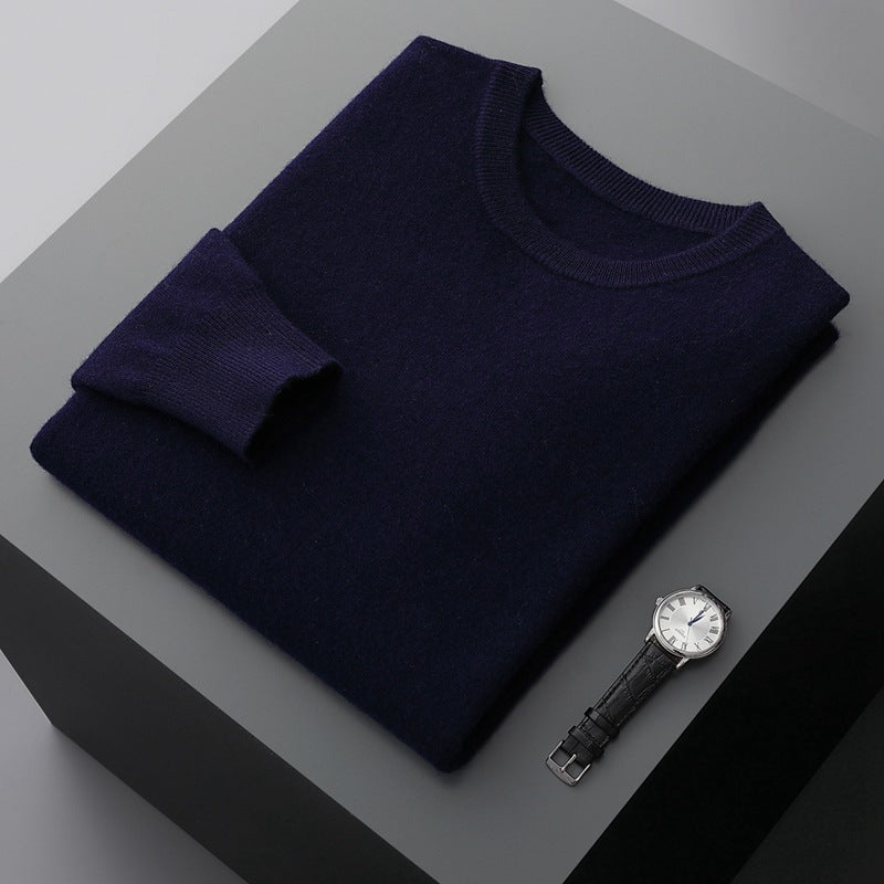 Maglione blu scuro piegato su tavolo grigio con orologio da polso nero; moda uomo elegante, abbigliamento invernale, accessori di lusso.