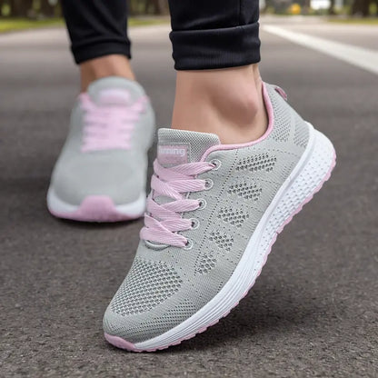 Scarpe da corsa grigie e rosa su strada asfaltata, design traspirante, suola ammortizzata, ideali per jogging e fitness.