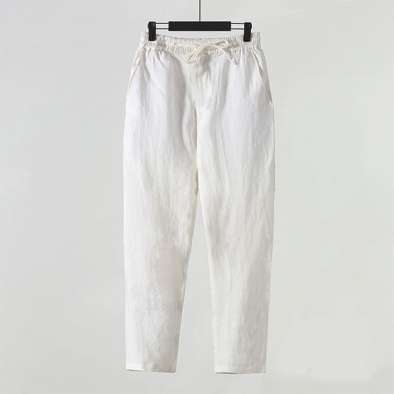 Pantaloni bianchi in cotone, stile casual, appesi su gruccia. Design semplice, ideale per moda estiva e abbigliamento quotidiano.