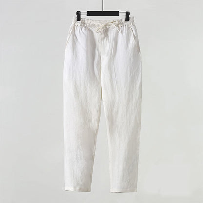 Pantaloni bianchi in cotone, stile casual, appesi su gruccia. Design semplice, ideale per moda estiva e abbigliamento quotidiano.