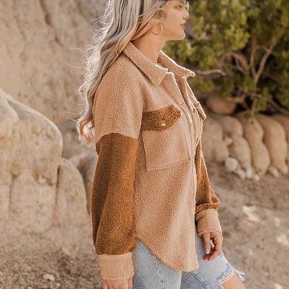 Donna con giacca in pile beige e marrone, jeans strappati, in un ambiente naturale roccioso. Moda autunnale, abbigliamento casual, stile outdoor.