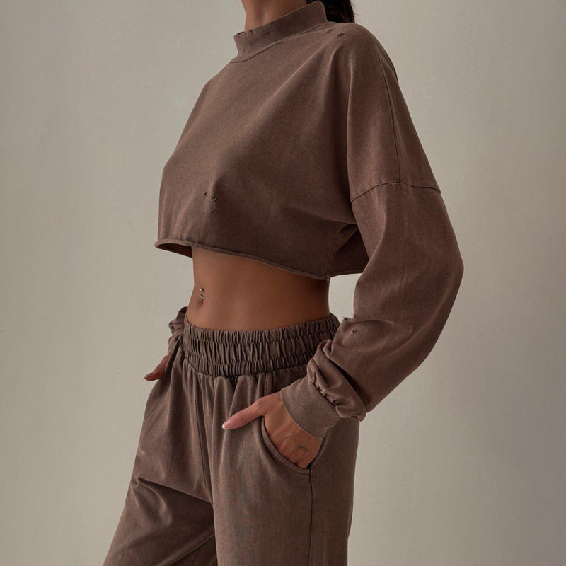 Donna in abbigliamento sportivo marrone, indossa un top corto e pantaloni con tasche. Stile casual, moda autunnale, abbigliamento comodo.