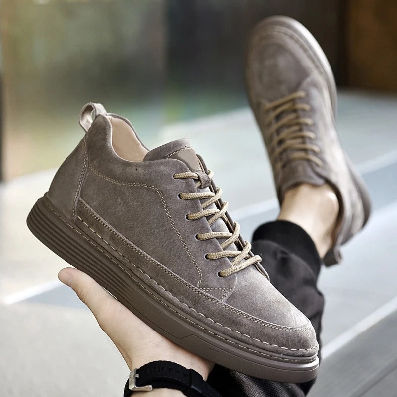 Scarpe da ginnastica in pelle scamosciata grigia, design casual, suola spessa, lacci coordinati, moda uomo, calzature eleganti e confortevoli.