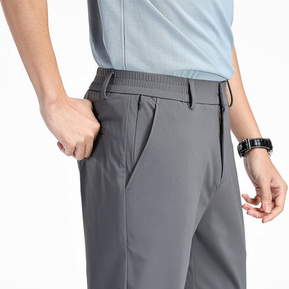 Uomo in pantaloni grigi sportivi con tasche, indossa una maglietta azzurra e orologio nero. Moda casual, abbigliamento comodo per attività all'aperto.