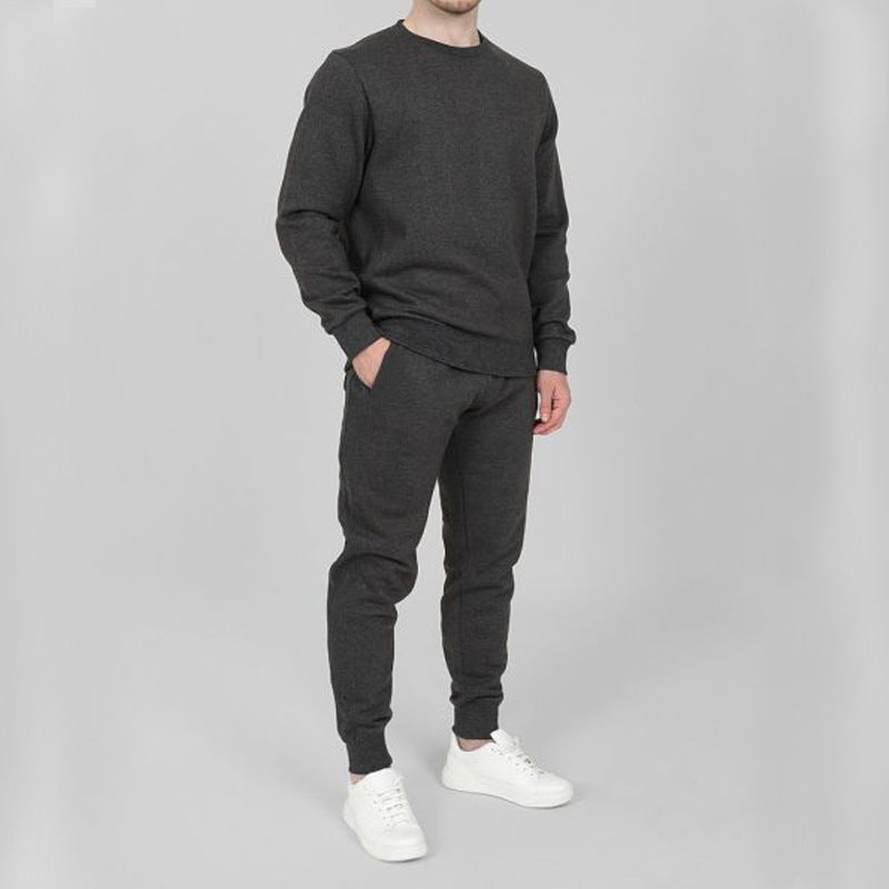 Uomo in tuta sportiva grigia, composta da felpa e pantaloni, con scarpe bianche. Abbigliamento casual e comodo per attività quotidiane.