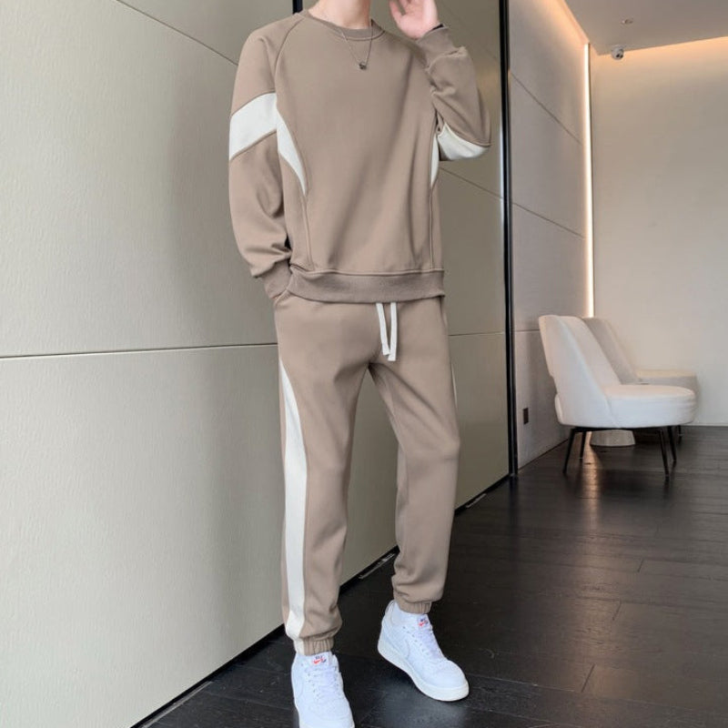 Uomo in tuta sportiva beige con dettagli bianchi, scarpe da ginnastica bianche, in un interno moderno. Moda casual, abbigliamento comodo.