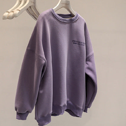 Felpa oversize viola appesa su gruccia, con scritta "Stress Less" sul petto. Moda casual, abbigliamento comodo, tendenza streetwear.