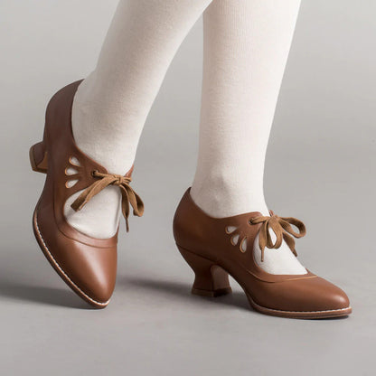 Scarpe da ballo vintage marroni con lacci, tacco medio e dettagli traforati, indossate con calze bianche. Eleganza retrò per danza classica.