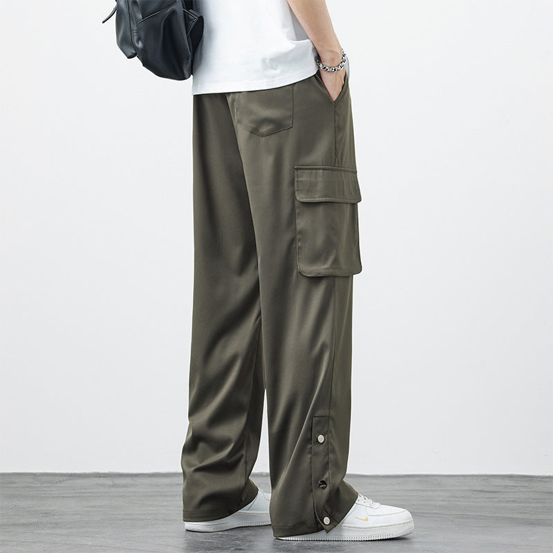 Pantaloni cargo verde oliva da uomo, tasche laterali ampie, stile casual, abbinati a scarpe bianche e zaino nero. Moda streetwear contemporanea.