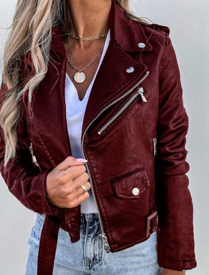 Giacca in pelle bordeaux da donna, stile motociclista, con zip argentate e dettagli metallici, indossata su maglietta bianca e jeans chiari.