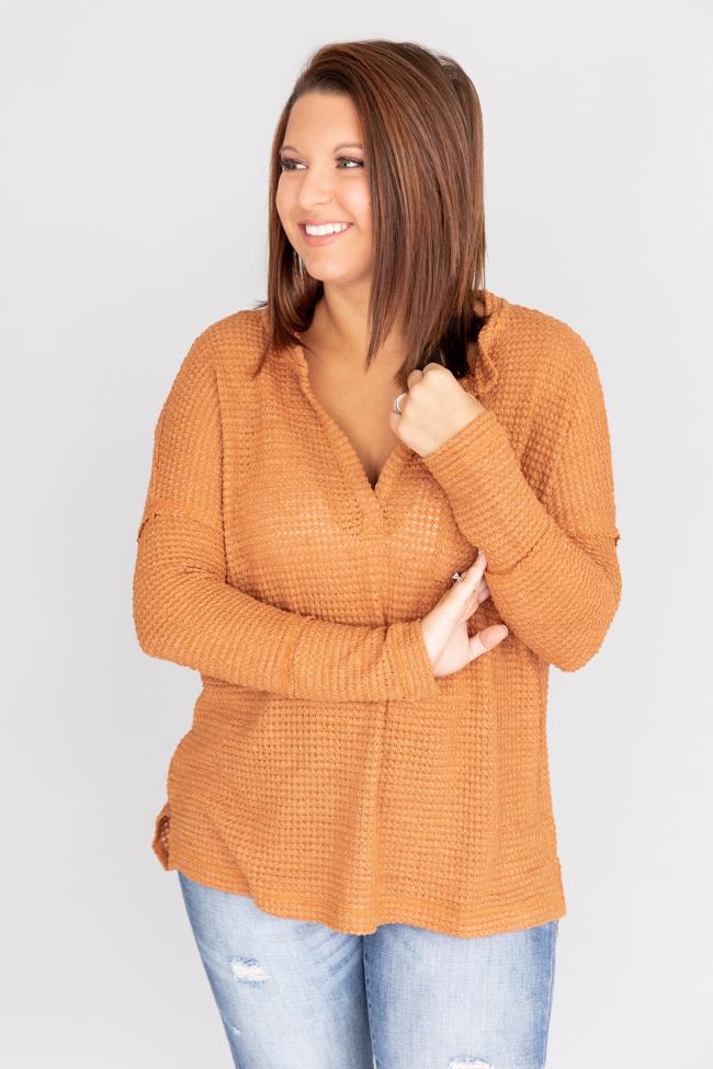 Donna sorridente con maglione arancione a maglia e jeans chiari, posa su sfondo bianco. Moda autunnale casual, abbigliamento femminile trendy.