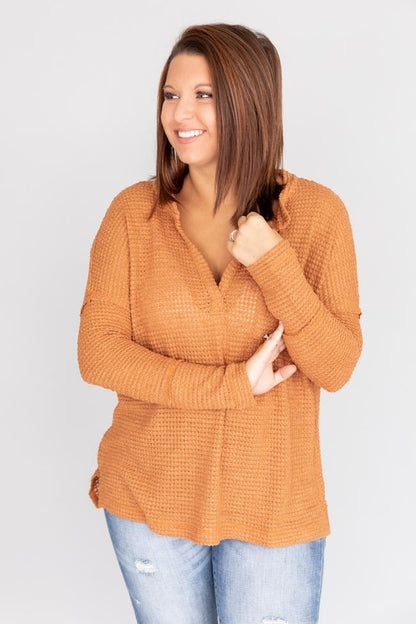 Donna sorridente con maglione arancione a maglia e jeans chiari, posa su sfondo bianco. Moda autunnale casual, abbigliamento femminile trendy.