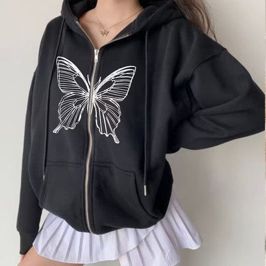Donna indossa felpa nera con cappuccio e stampa farfalla bianca, abbinata a gonna plissettata bianca. Moda casual, abbigliamento streetwear.