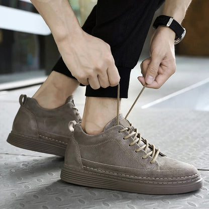 Scarpe da ginnastica uomo in pelle scamosciata grigia, lacci allacciati, suola spessa, stile casual, moda urbana, pavimento metallico.