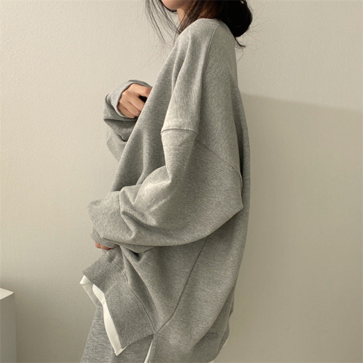 Donna con felpa oversize grigia, moda casual minimalista, abbigliamento comodo, stile autunnale, tendenza streetwear femminile.