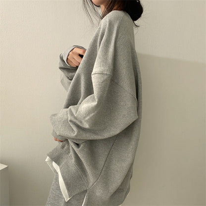 Donna con felpa oversize grigia, moda casual minimalista, abbigliamento comodo, stile autunnale, tendenza streetwear femminile.