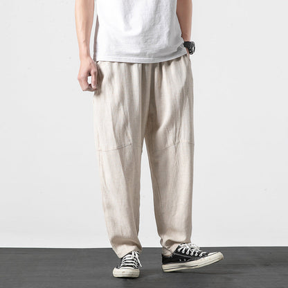 Pantaloni larghi in lino beige, indossati con t-shirt bianca e sneakers nere. Moda casual uomo, stile estivo, abbigliamento comodo.