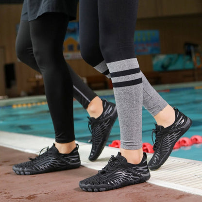 Due persone camminano a bordo piscina indossando scarpe da acqua nere e leggings sportivi. Scarpe da nuoto, abbigliamento sportivo, piscina.