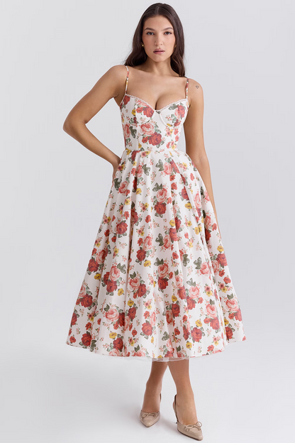 Donna in abito floreale estivo bianco e rosso, scollo a cuore, lunghezza midi, spalline sottili. Moda femminile elegante, tendenze abbigliamento 2023.