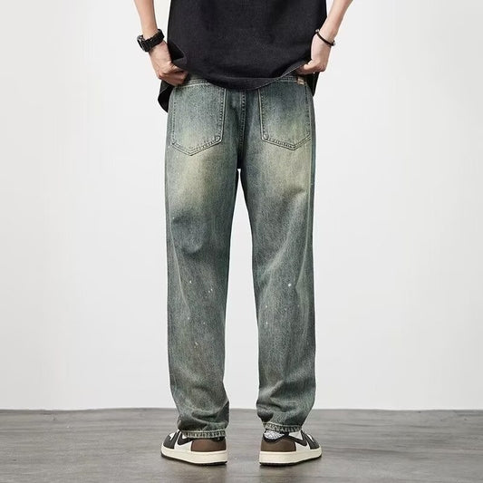 Jeans larghi da uomo in denim blu slavato, stile casual, con tasche posteriori, indossati con sneakers bianche e nere su sfondo neutro.