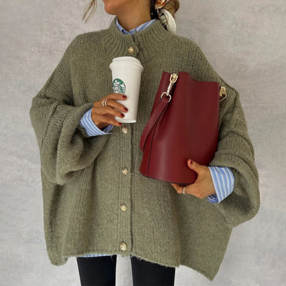 Donna con cardigan oversize verde, camicia a righe blu, borsa rossa e bicchiere di caffè Starbucks. Moda autunnale casual chic.