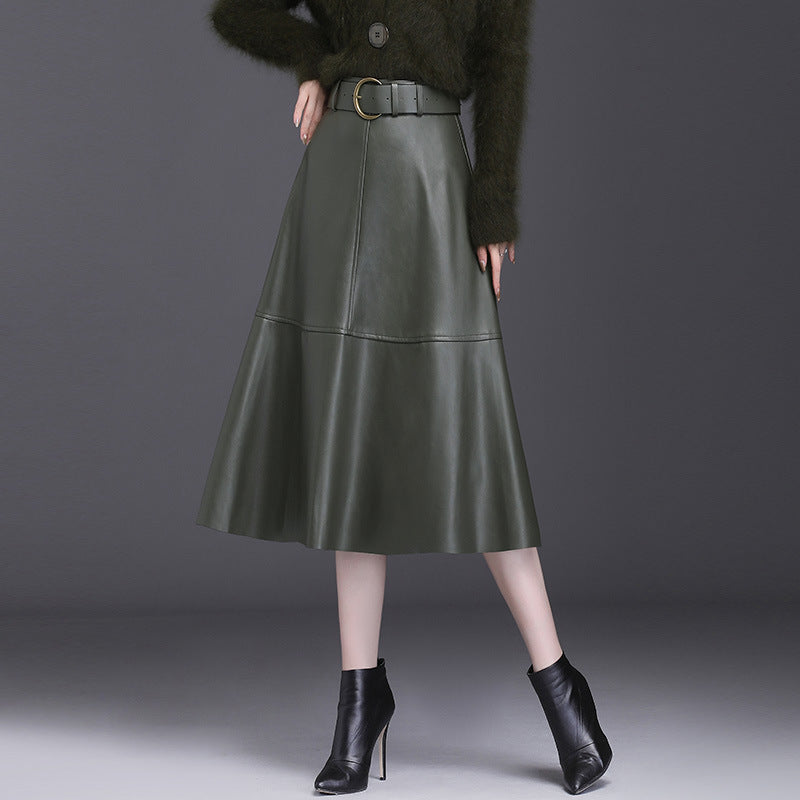 Gonna midi in pelle verde scuro con cintura, abbinata a stivaletti neri con tacco. Moda autunnale elegante e sofisticata.