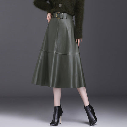 Gonna midi in pelle verde scuro con cintura, abbinata a stivaletti neri con tacco. Moda autunnale elegante e sofisticata.