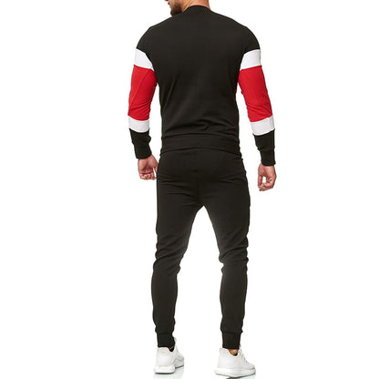 Uomo in tuta sportiva nera con dettagli rossi e bianchi, vista posteriore. Indossa scarpe da ginnastica bianche. Moda casual maschile.