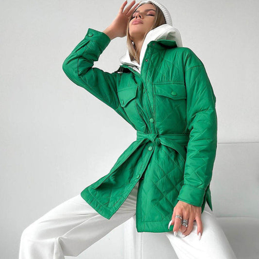 Donna con giacca trapuntata verde, cappuccio bianco e pantaloni bianchi. Moda autunnale, stile casual chic, tendenze abbigliamento 2023.