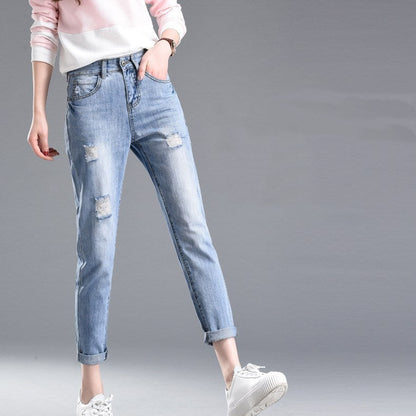 Jeans strappati da donna, stile casual, abbinati a una felpa rosa e scarpe bianche, moda giovane, tendenze abbigliamento 2023.
