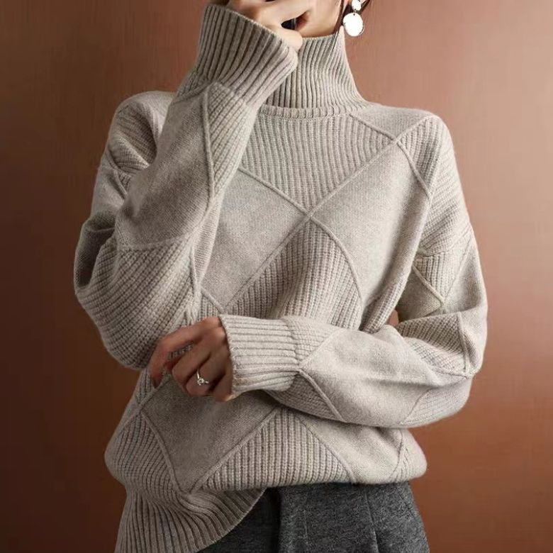 Maglione a collo alto beige, design a rombi, indossato da una persona. Stile elegante e moderno, perfetto per l'autunno e l'inverno.
