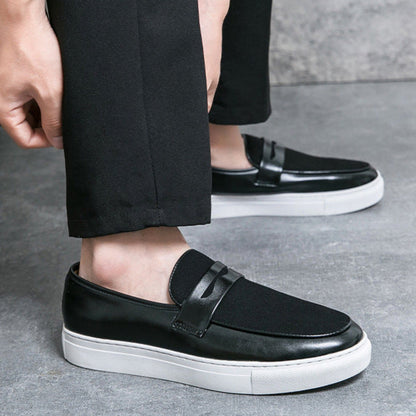 Scarpe slip-on nere eleganti da uomo, suola bianca, indossate con pantaloni neri. Calzature moderne e comode per look casual e formali.
