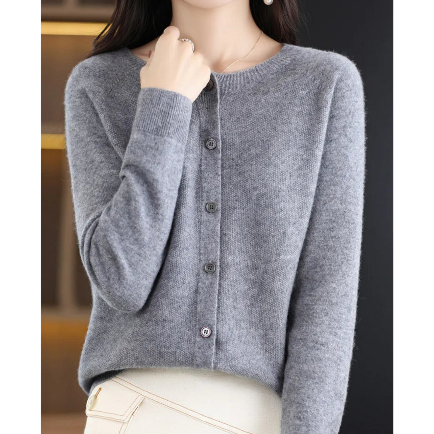 Maglione grigio in cashmere, donna, maniche lunghe, abbottonato, elegante, moda autunno inverno, sfondo nero, stile casual chic.