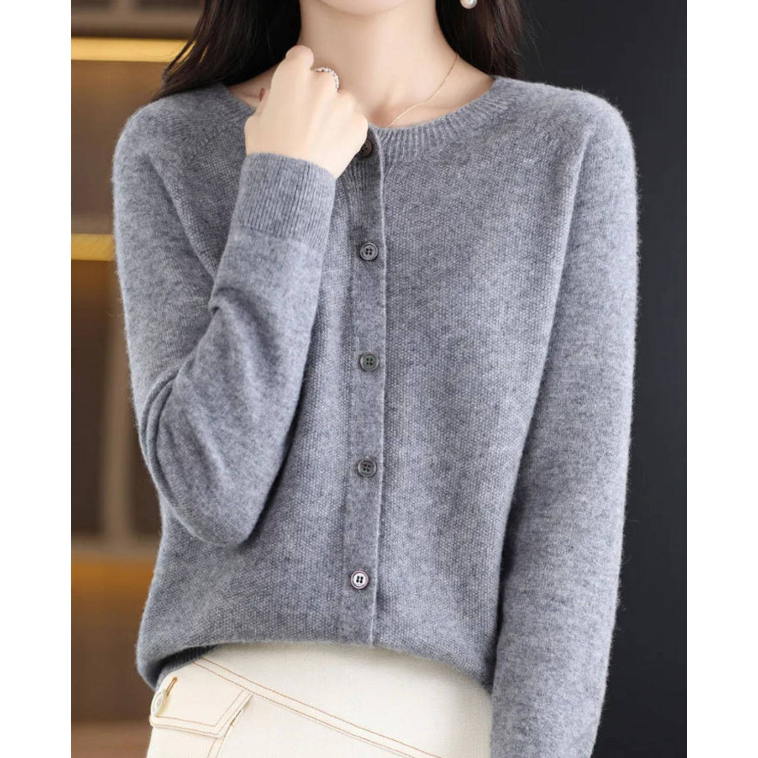 Maglione grigio in cashmere, donna, maniche lunghe, abbottonato, elegante, moda autunno inverno, sfondo nero, stile casual chic.