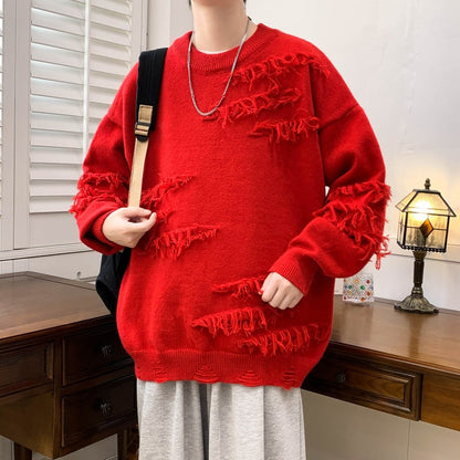 Maglione rosso oversize con dettagli strappati, indossato da una persona con zaino nero. Arredamento vintage con lampada e scrivania in legno.