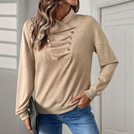Donna con maglione beige a collo alto con bottoni, jeans blu, in posa casual in un interno moderno. Moda autunnale, abbigliamento femminile elegante.