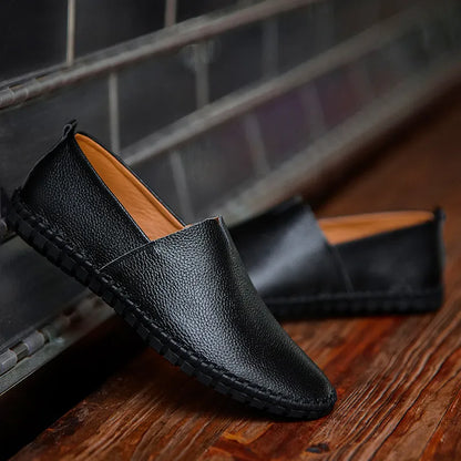Scarpe mocassini in pelle nera su pavimento in legno, design elegante e moderno, ideali per uomo, calzature casual e formali, comfort e stile.