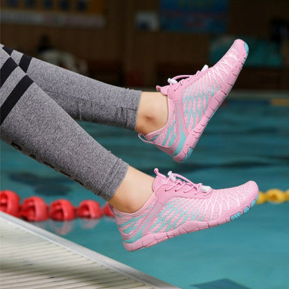 Scarpe da ginnastica rosa e azzurre indossate da una persona vicino a una piscina, leggings grigi, design sportivo, calzature leggere per nuoto e fitness.