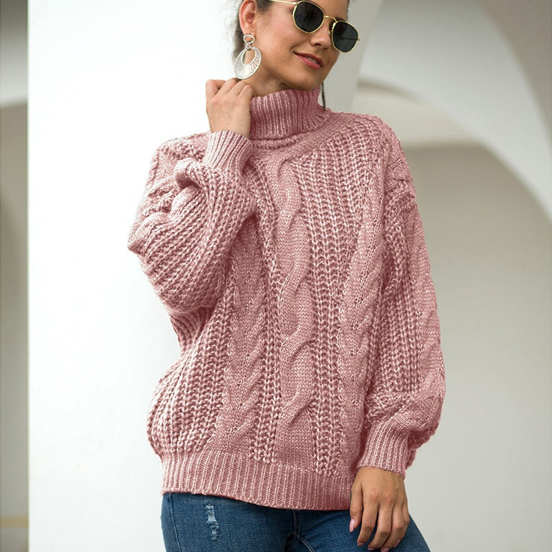 Donna con maglione rosa a trecce, occhiali da sole e orecchini pendenti, posa in un ambiente moderno. Moda autunnale, stile casual chic.