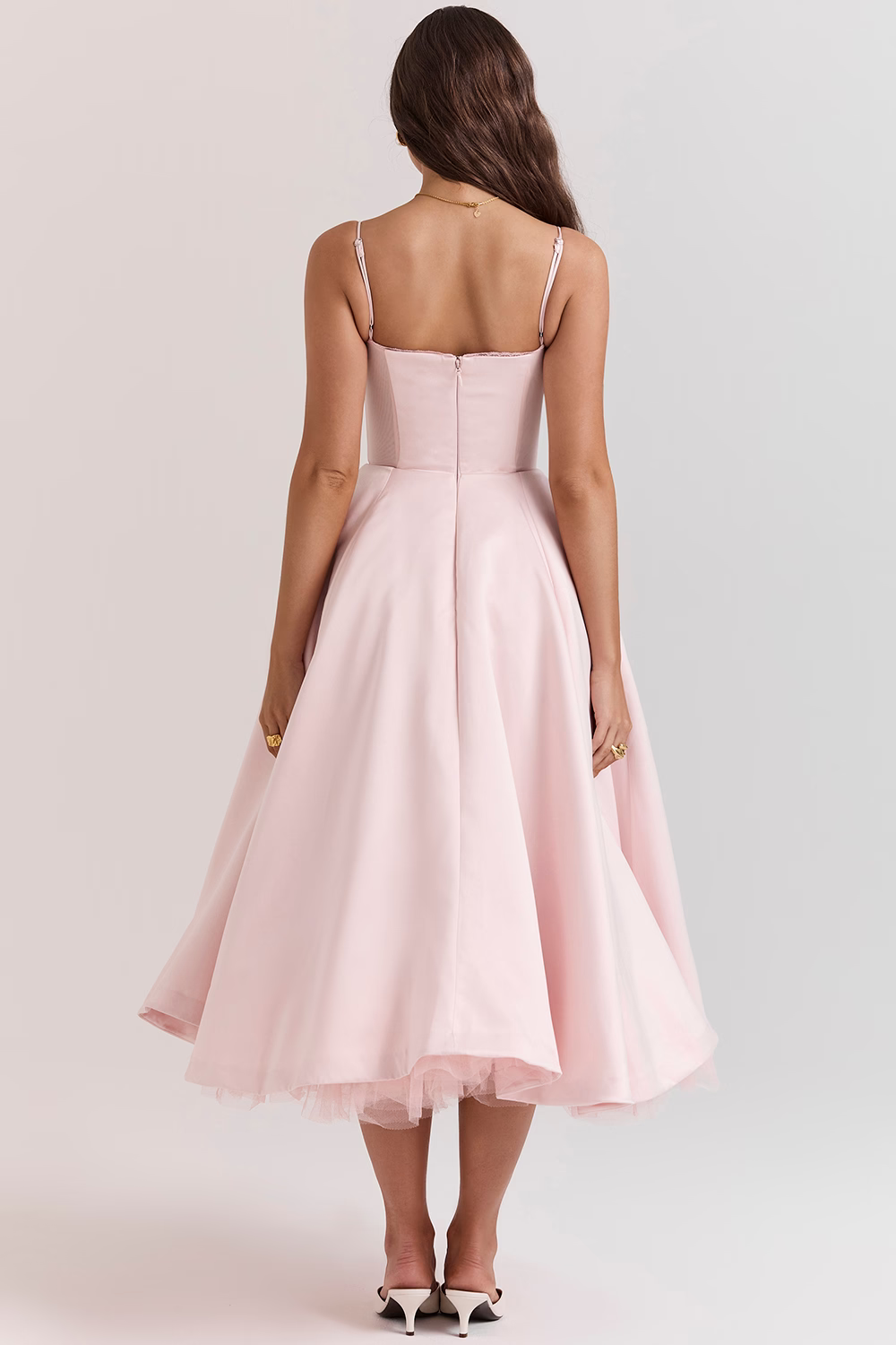 Donna in abito rosa chiaro elegante, lunghezza media, con spalline sottili, vista posteriore. Moda femminile, abbigliamento da sera, stile sofisticato.