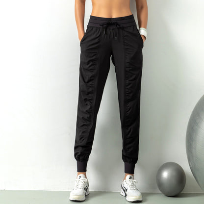 Pantaloni sportivi neri da donna, con tasche e coulisse, indossati con scarpe da ginnastica bianche. Fitness, moda sportiva, abbigliamento comodo.