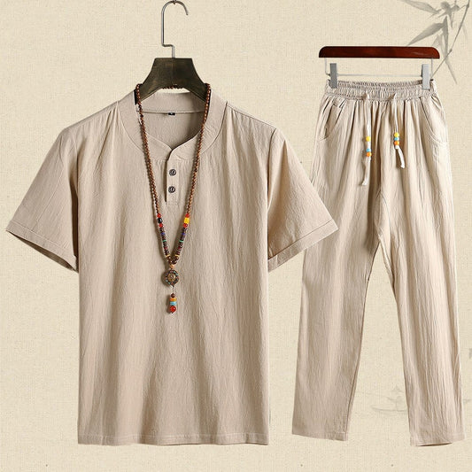 Completo estivo uomo in cotone beige, composto da maglietta a maniche corte e pantaloni, con collana etnica decorativa. Abbigliamento casual elegante.