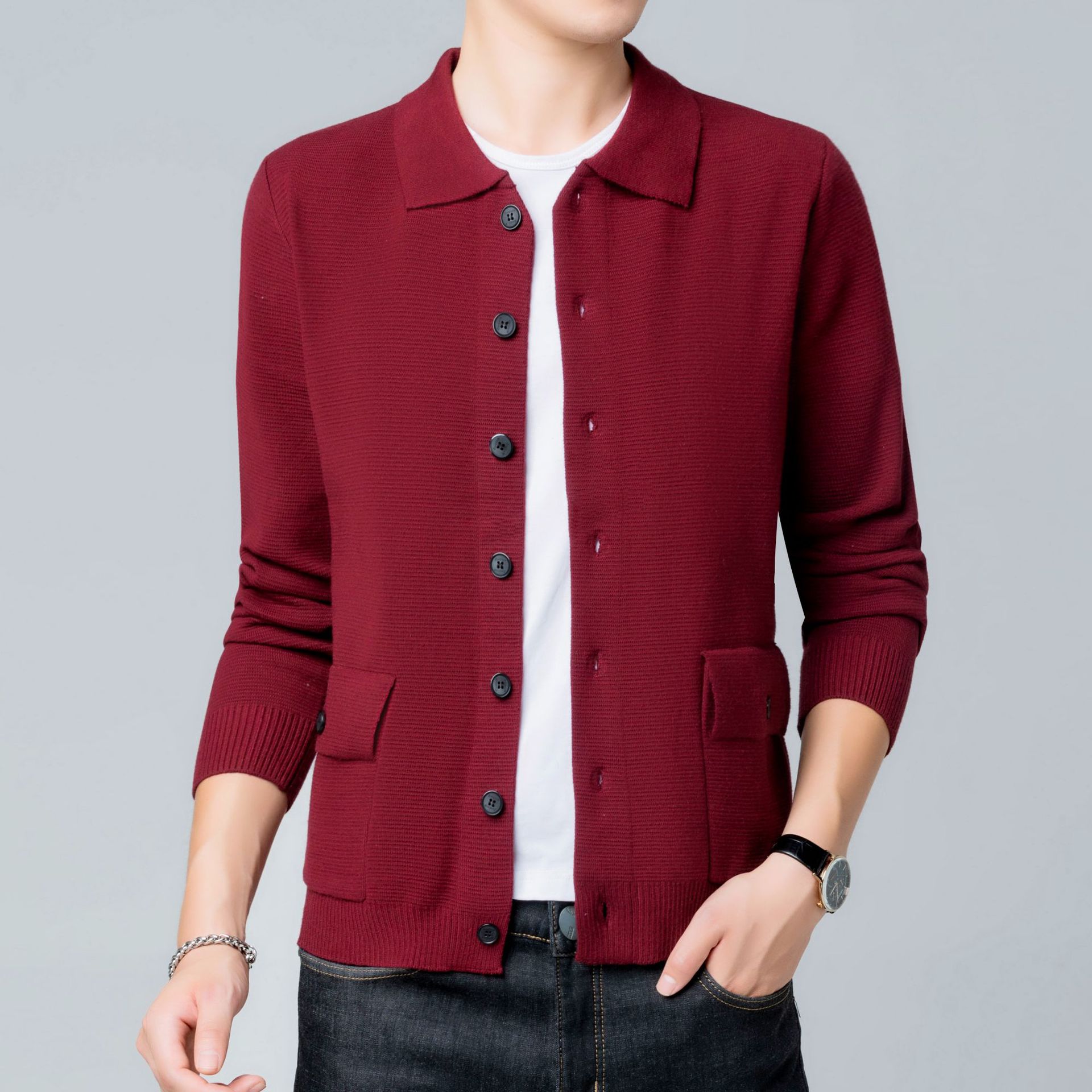 Maglione cardigan uomo bordeaux, maniche lunghe, bottoni neri, tasche frontali, indossato su t-shirt bianca e jeans. Moda casual elegante.