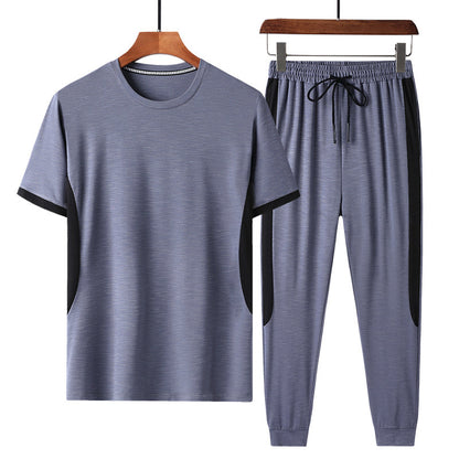 Completo sportivo uomo grigio, maglietta a maniche corte e pantaloni con coulisse, design moderno, tessuto traspirante, ideale per palestra e fitness.