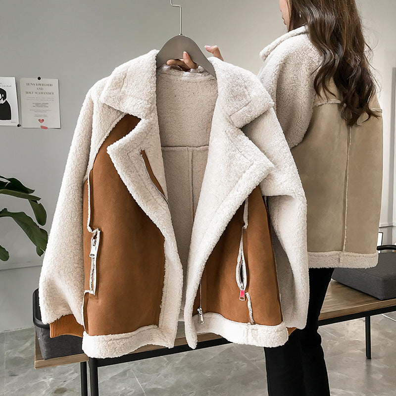 Giacca invernale in pile bianco con dettagli in pelle marrone, appesa su gruccia. Moda donna, abbigliamento caldo, stile casual chic.
