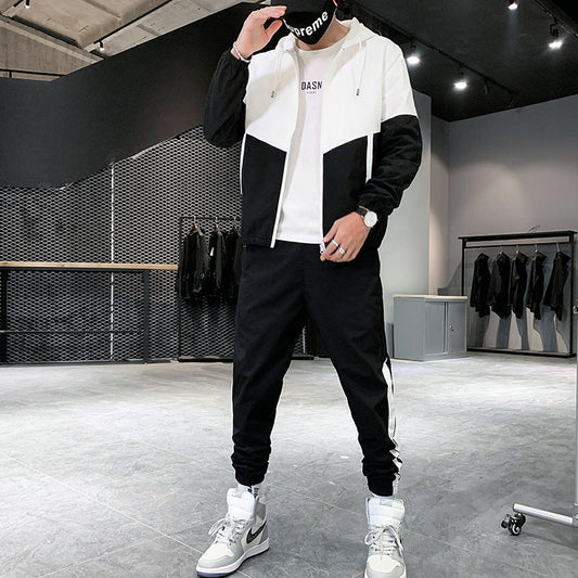 Uomo in tuta sportiva bianca e nera, cappuccio, scarpe da ginnastica grigie e bianche, in negozio di abbigliamento moderno. Moda streetwear casual.