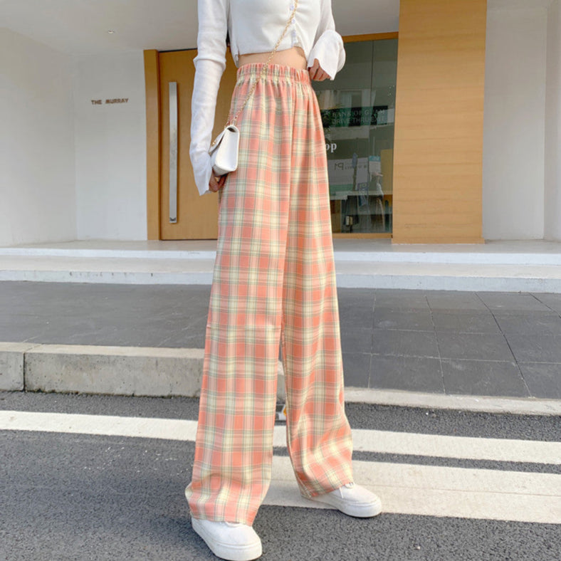 Pantaloni a quadri larghi donna, vita alta, colori pastello, abbinati a top bianco corto e sneakers bianche, moda casual urbana.